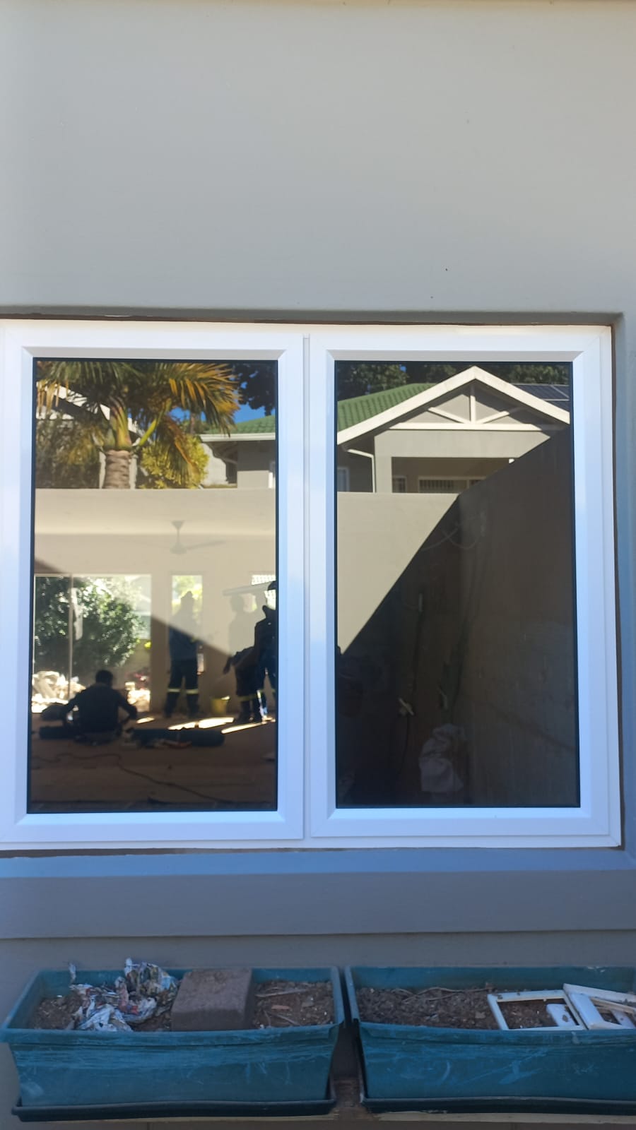White aluminium window frames reflecting a Hillcrest garden